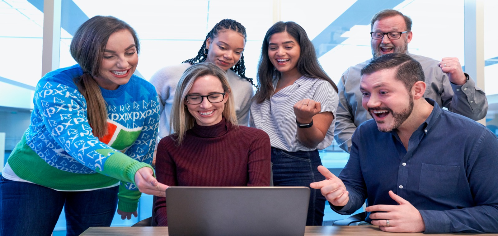 Creative team reviewing a laptop while comparing Creative Cloud student plan options